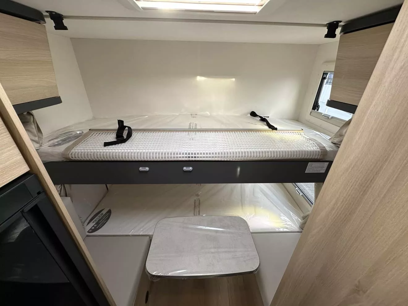 Intérieur d'un camping-car avec lit superposé et rangements en bois clair.
