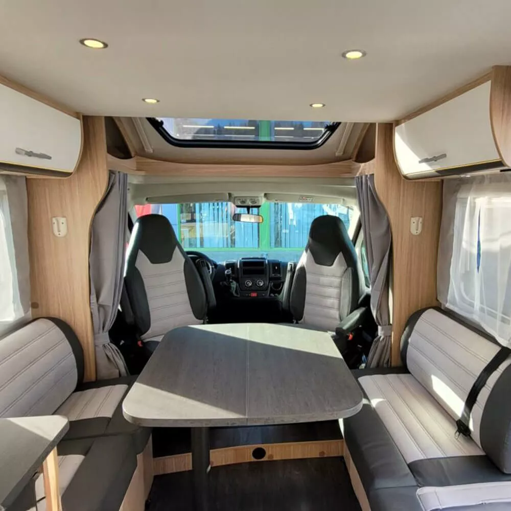 Intérieur d'un camping-car moderne avec table et sièges en cuir gris.