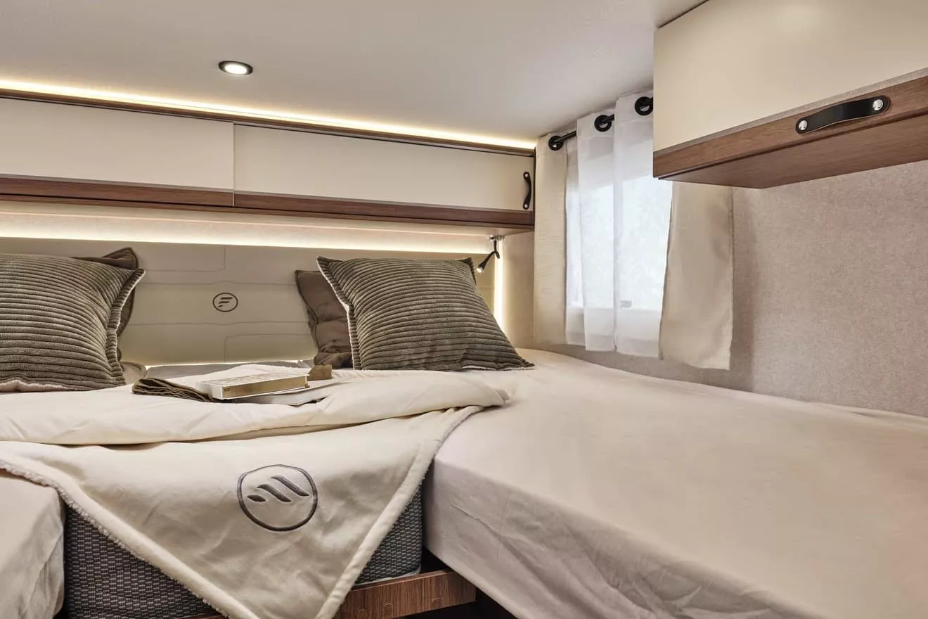 Intérieur d'une chambre de camping-car avec lit double et éclairage LED.