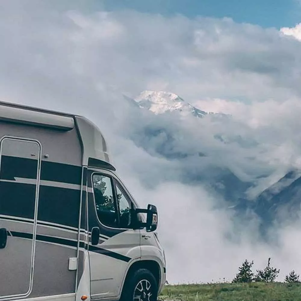Camping-car stationné devant un paysage montagneux nuageux